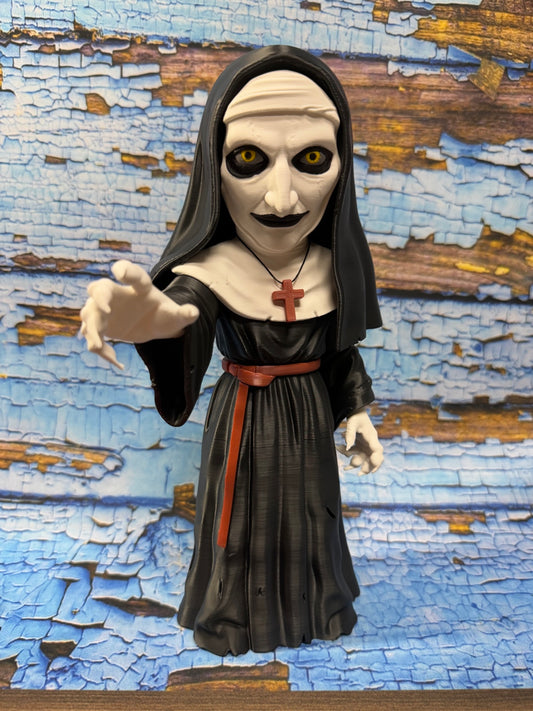 Black and white 3D-printed creepy nun collectible with yellow eyes and red cross